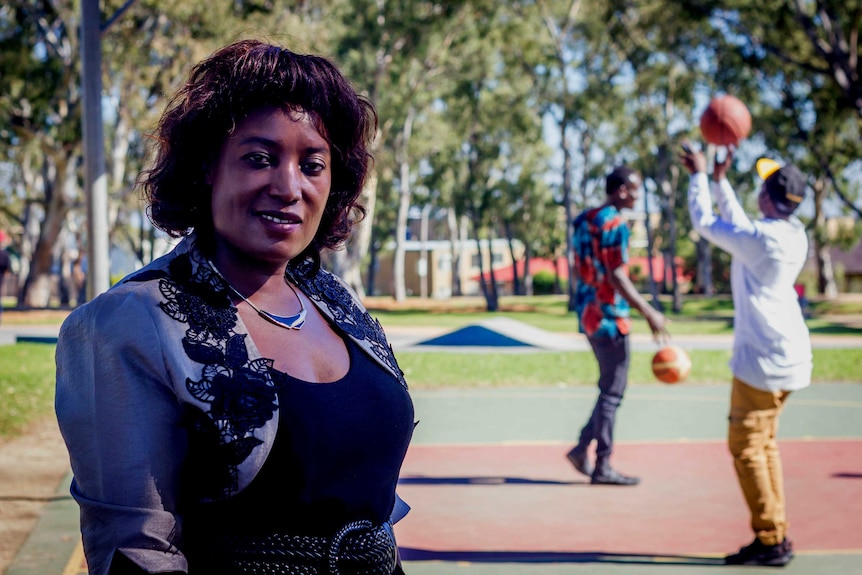A smiling woman stands in front of a basketball court.