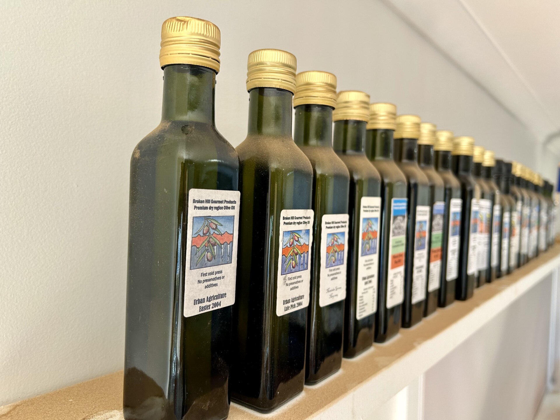 Bottles of oil lined up in a row on a shelf. 