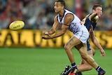 Danyle Pearce of the Fremantle Dockers handballs a yellow football with an Adelaide Crows player behind him.