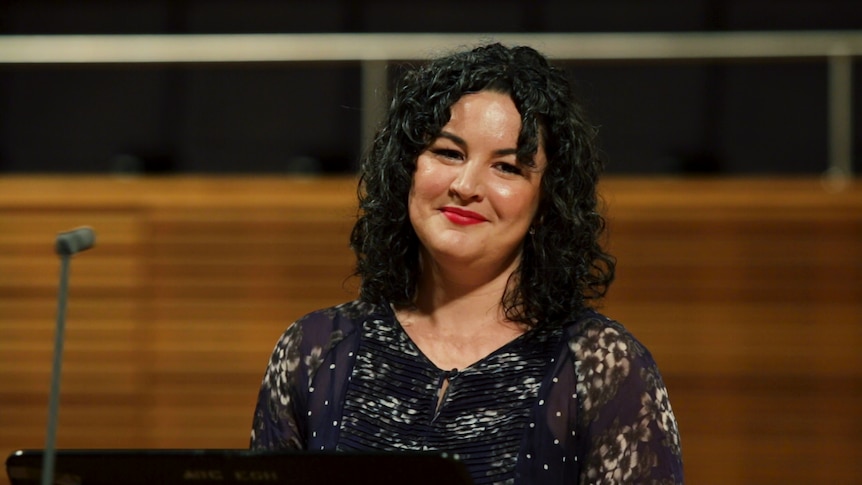 Mezzo-soprano Ruth Strutt stands in front of a microphone in the ABC's Eugene Goossens hall.