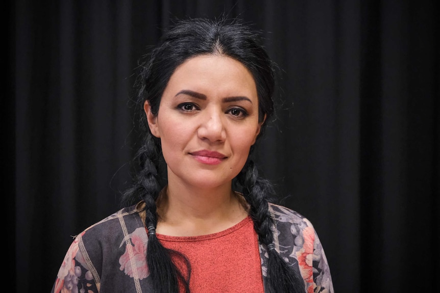 Maryam Zahid smiling at the camera in front of a black curtain.