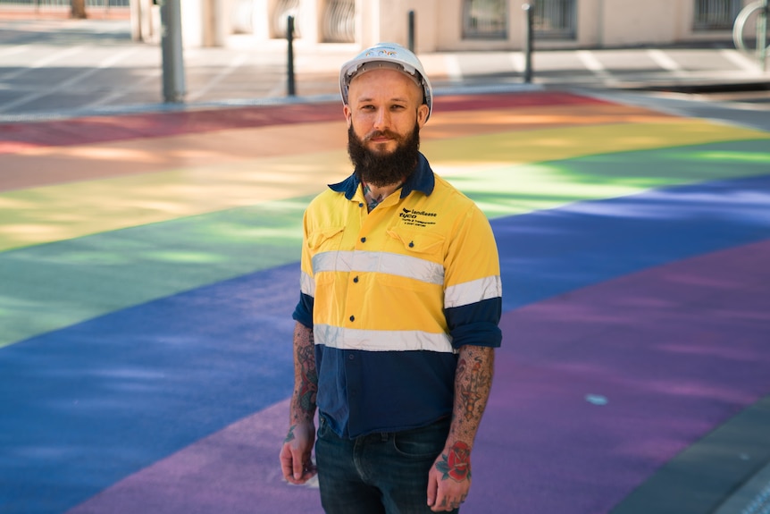 A bearded man wearing hi-vis and a white helmet