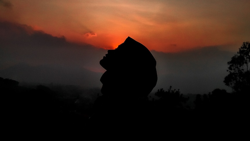 A woman in a hijab at sunset.