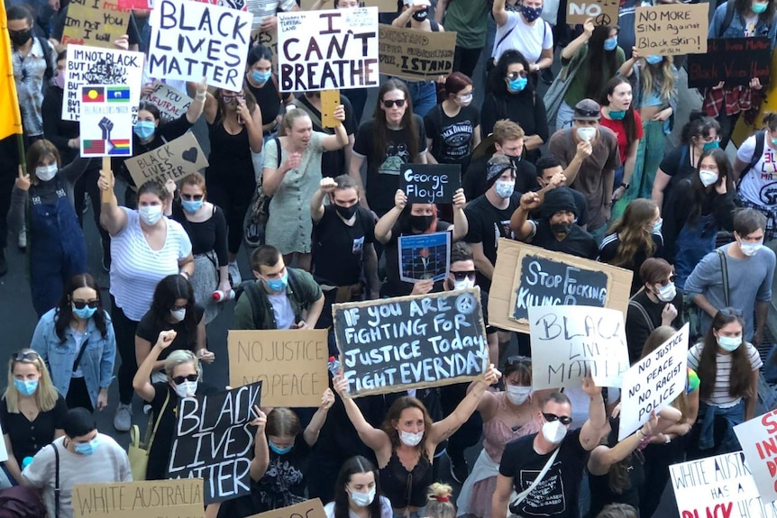 protesters holding black lives matter signs and wearing masks march in Brisbane