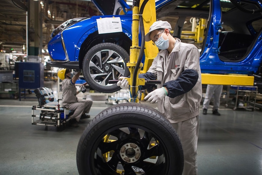 A workers tightening a tire in a factory.