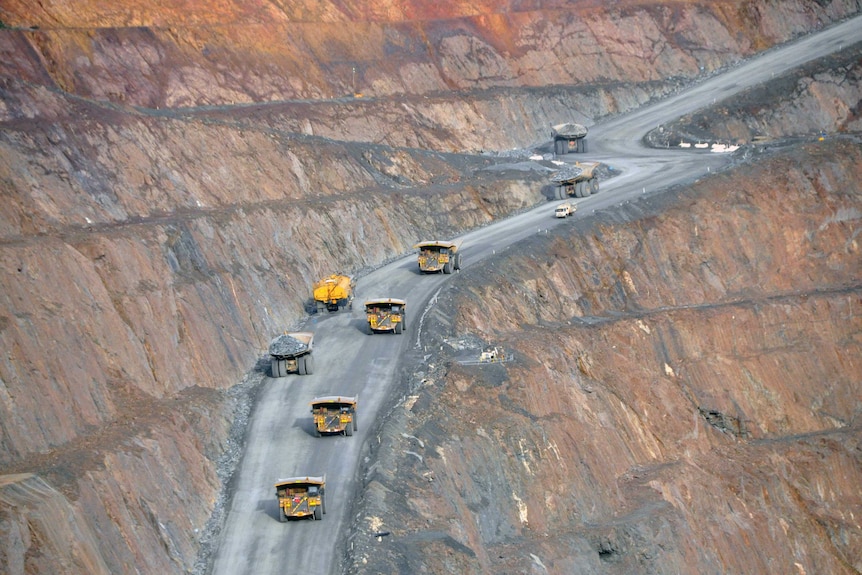 A long shot of dump trucks driving up and down Kalgoorlie's Superpit open cut gold mine.