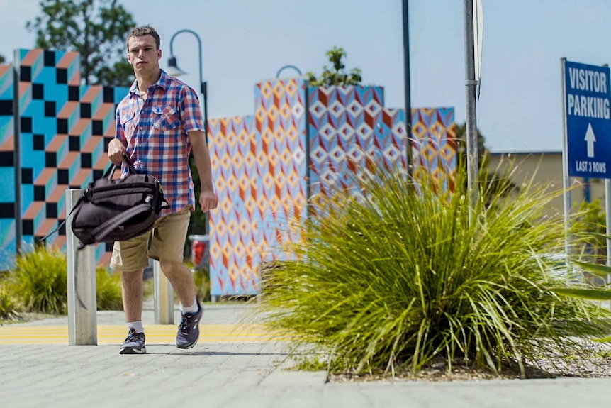 Young man carrying a backpack walking on a footpath for a story about getting employment when you have a disability