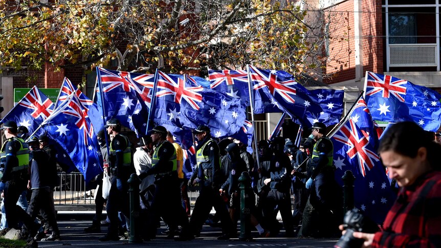 Right wing protesters from the UPF and the True Blue Crew march to Carlton Gardens with Australian flags.