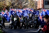 Right wing protesters from the UPF and the True Blue Crew march to Carlton Gardens with Australian flags.