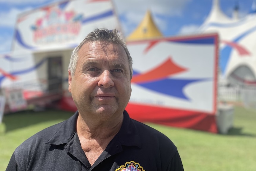 A man with grey hair in front of a circus set up