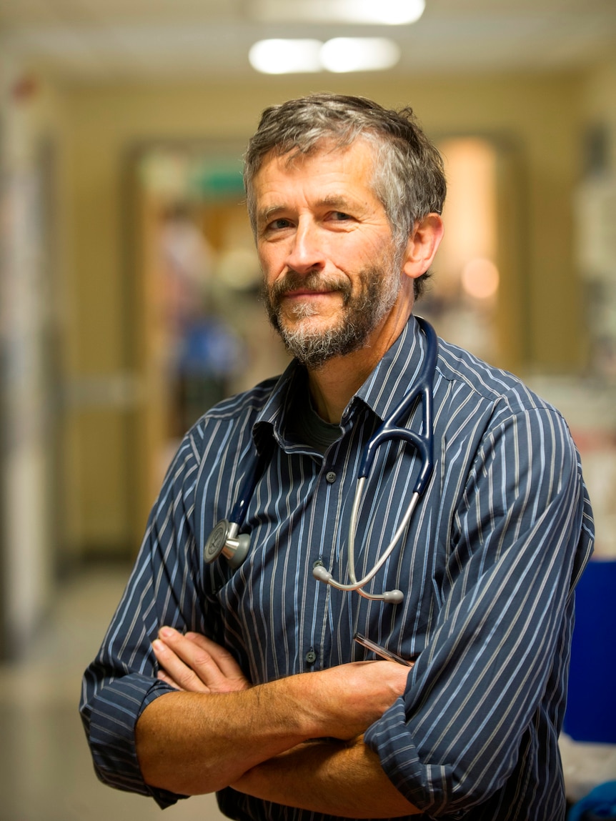 A doctor in a striped shirt poses with a stethoscope around his neck