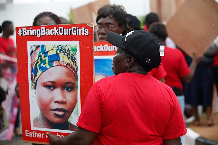 A woman carrying a portrait of Esther Ayuba attends a street protest campaigning for the rescue of abducted Chibok girls.