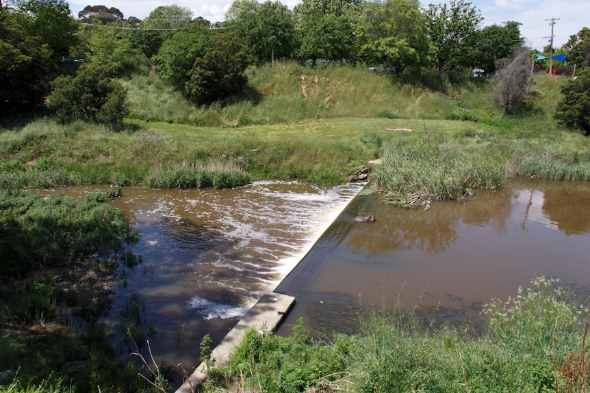 Brown water flows down a river.