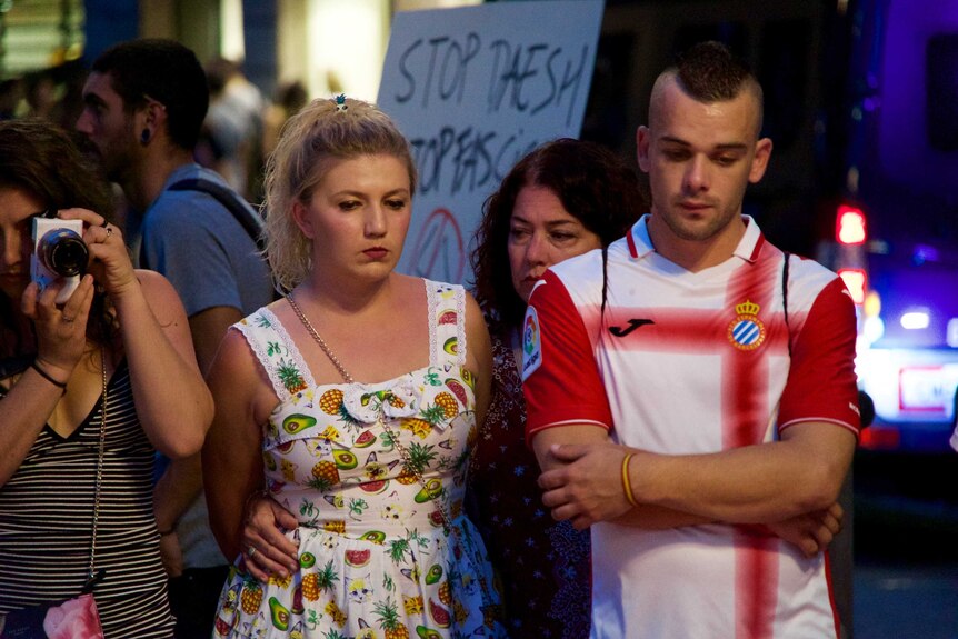 People look solemn as they stand paying tribute to spain victims.