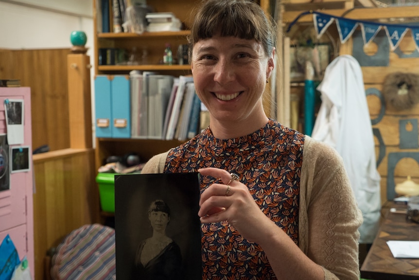 Aurelia hold a tintype photograph of herself.