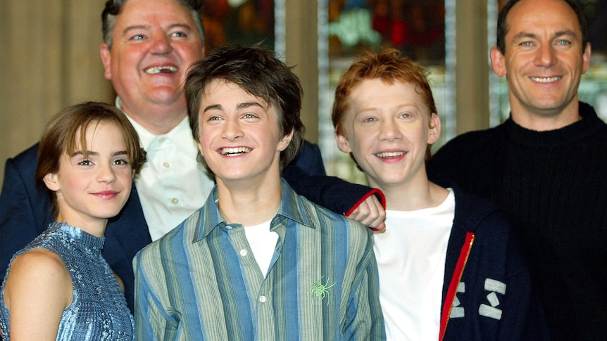 watson, radcliffe and grint as young teenagers smiling on red carpet, coltrane and isaacs smiling behind them