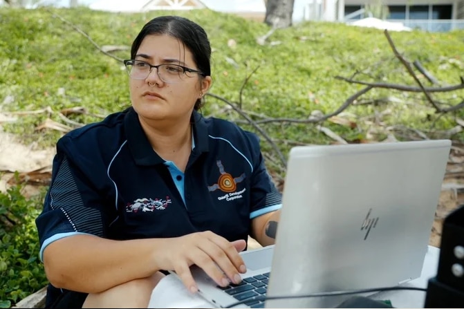 A woman looking off into the distance with a laptop in front of her