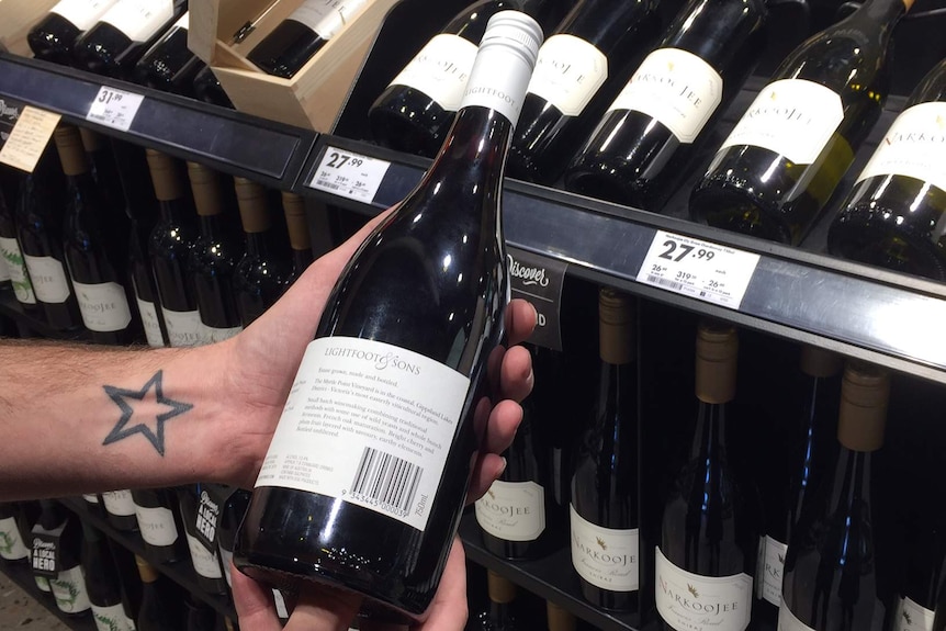 Customer holding a wine bottle in their hand, reading label.