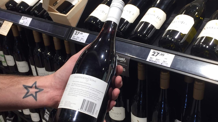 Customer holding a wine bottle in their hand, reading label.