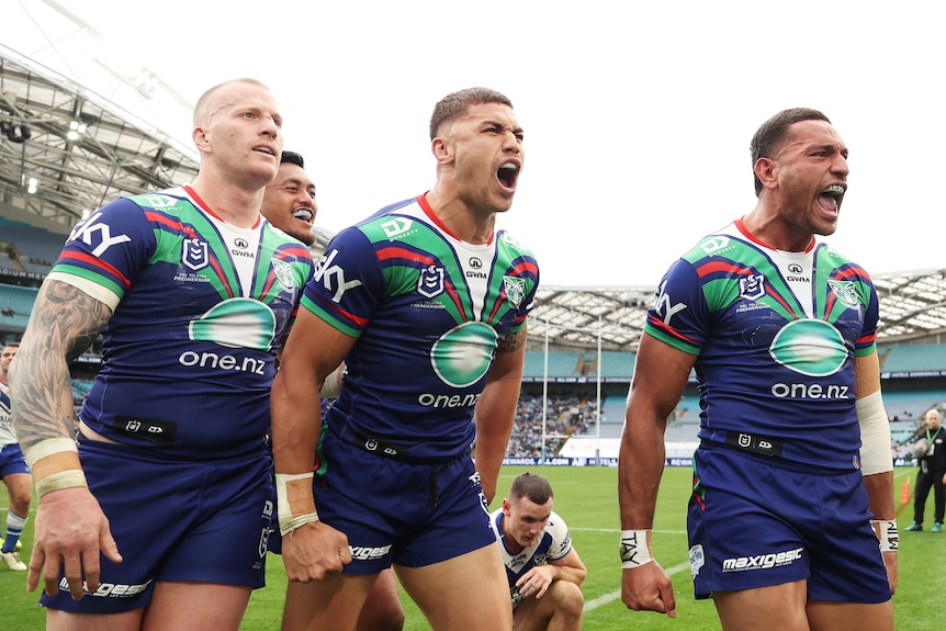 Three Warriors players shout to celebrate an NRL try.