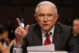 Jeff sessions gestures with his right hand and wears a red tie at the table at the committee hearing