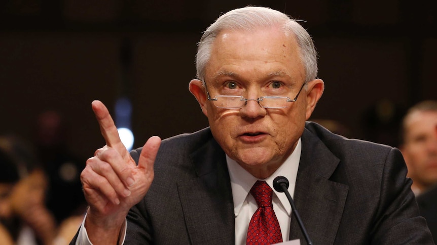 Jeff sessions gestures with his right hand and wears a red tie at the table at the committee hearing