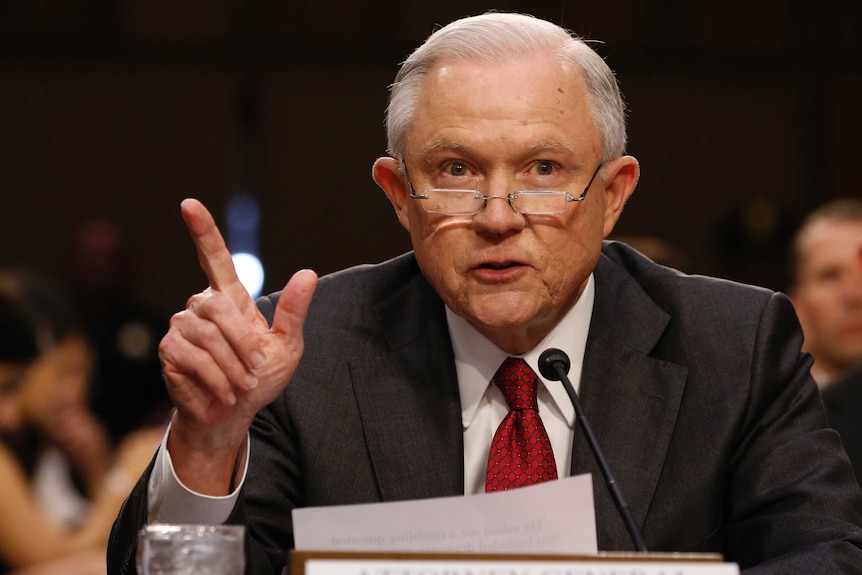 Jeff sessions gestures with his right hand and wears a red tie at the table at the committee hearing