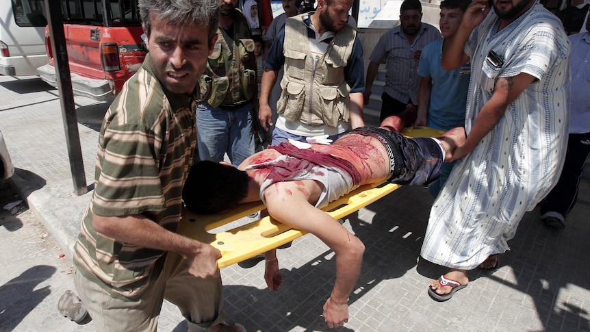 Syrians rush a civilian wounded in shelling on the northern city of Aleppo on August 4, 2012.