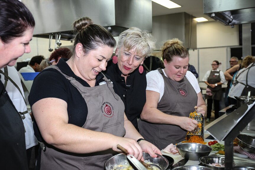 Maggie Beer standing between two women at cooking workshop