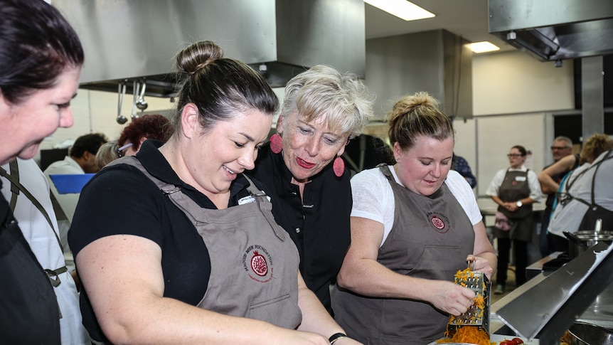Maggie Beer standing between two women at cooking workshop