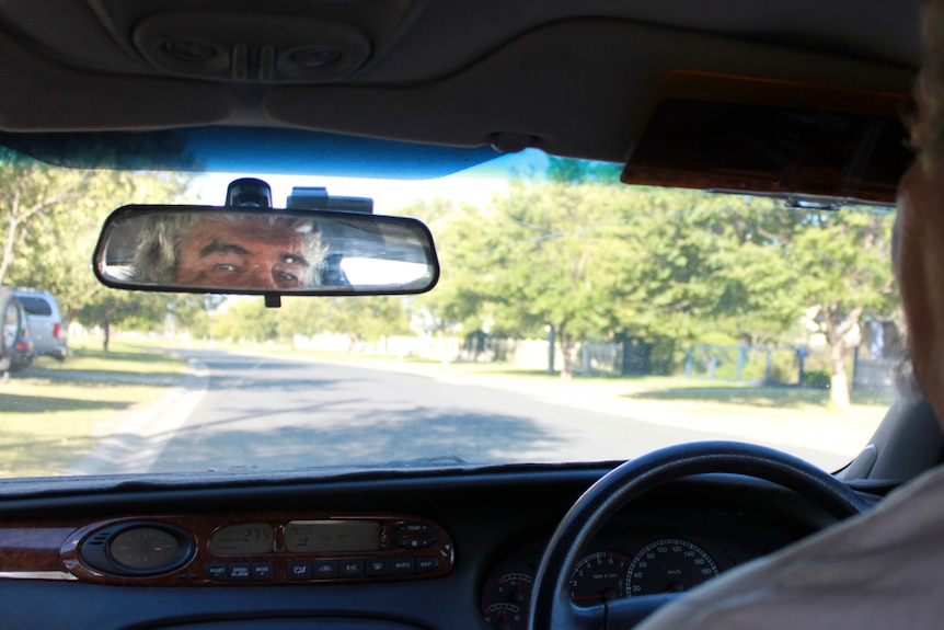A taxi driver looks through his rear vision mirror.