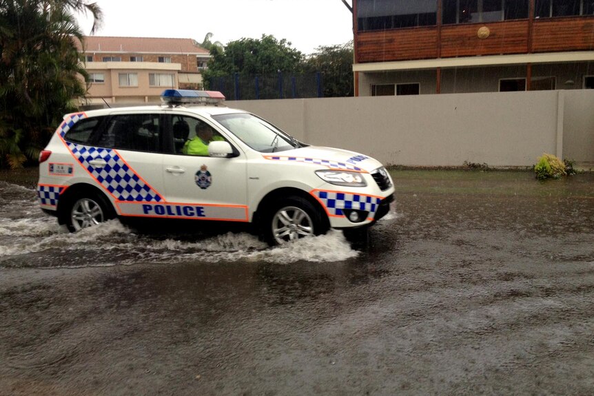 Police drive through water covering a street on Queensland's Gold Coast during torrential rain.