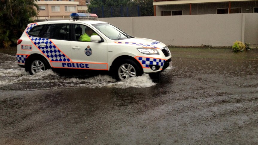 Police drive through water covering a street on Queensland's Gold Coast during torrential rain.