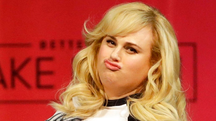 Rebel Wilson pouts in front of a red background.