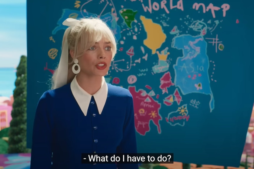 A screenshot from the Barbie trailer showing Margot Robbie in front of a crudely drawn world map. 