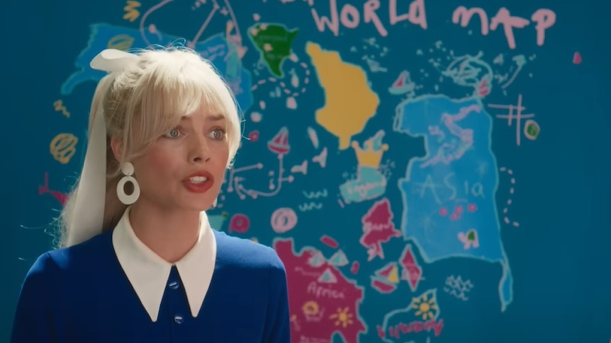 A screenshot from the Barbie trailer showing Margot Robbie in front of a crudely drawn world map. 