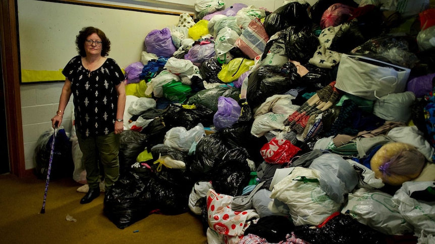Zions Hill Op Shop manager Susan Clarke in front of large pile of rubbish