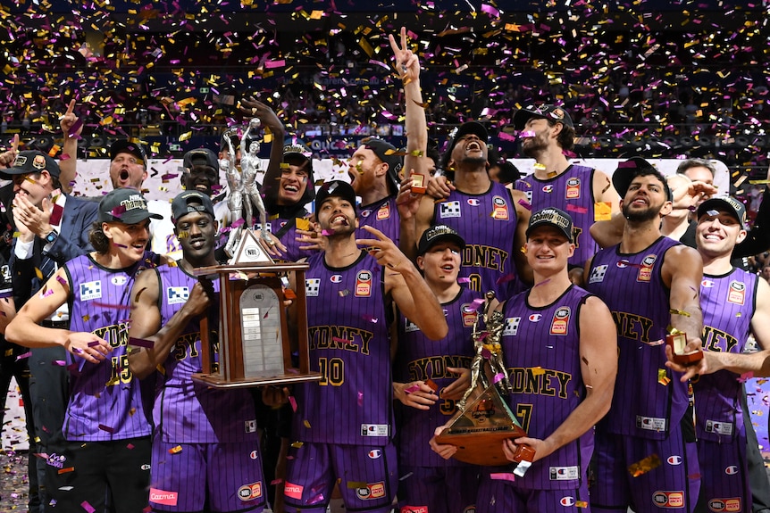 A basketball team celebrates with a trophy.