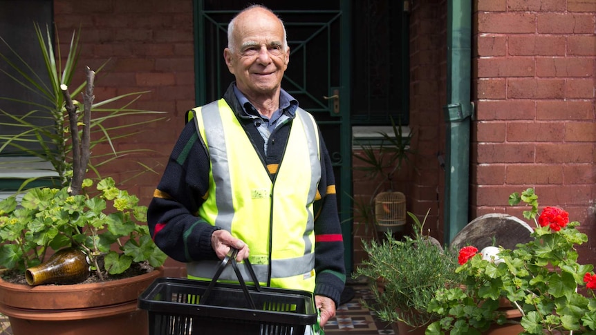 John Karlick stands outside a house before delivering a meal to an elderly resident.