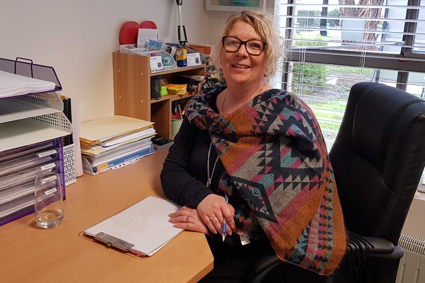 Counsellor Jo White sits at the desk in her office writing on a piece of paper.