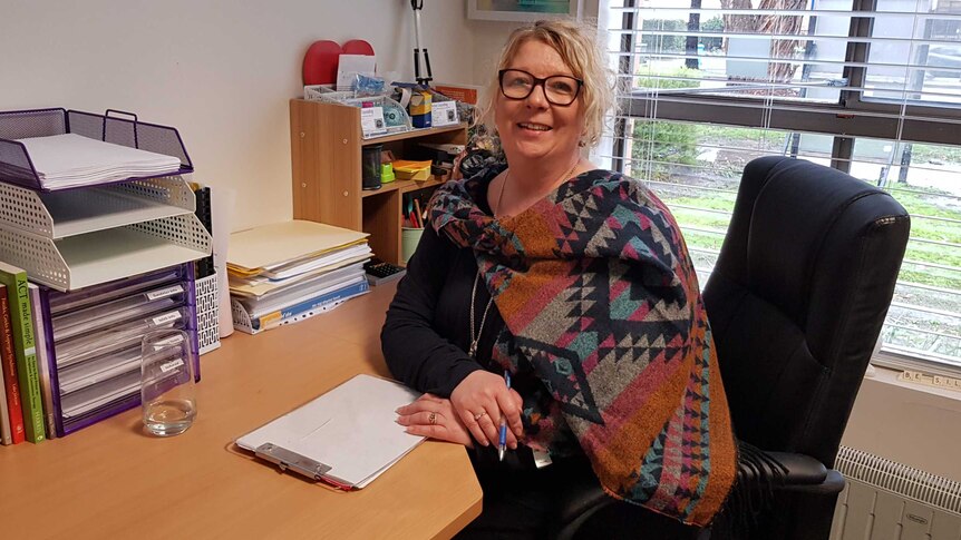 Counsellor Jo White sits at the desk in her office writing on a piece of paper.