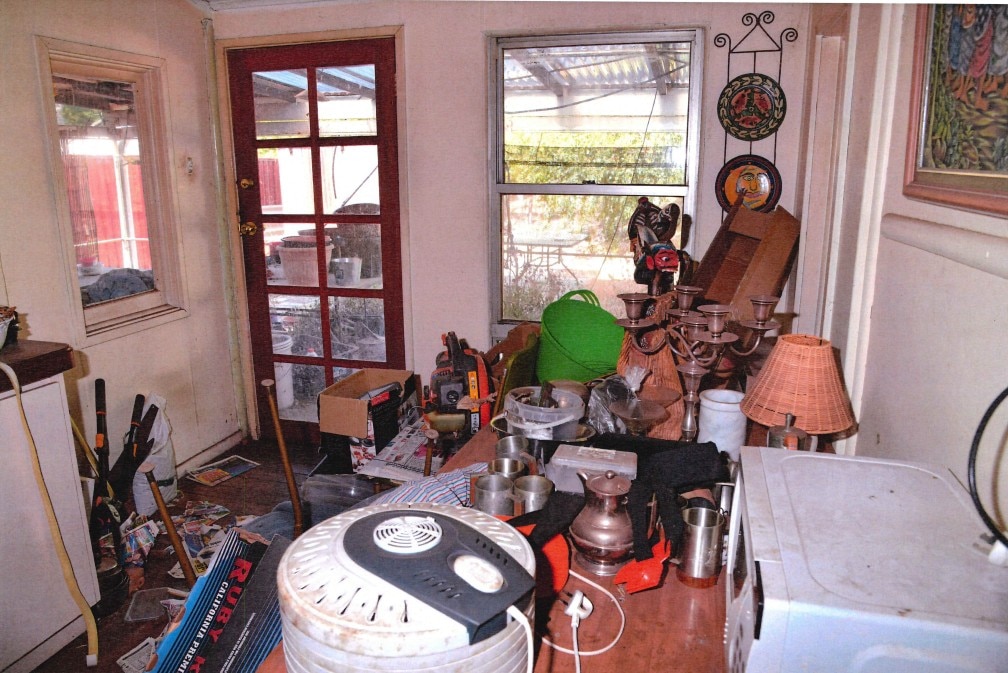 A back door into a cluttered room pictured in the daylight
