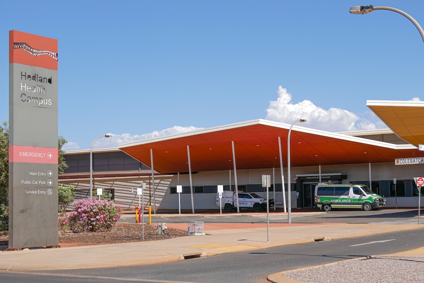 A hospital in Hedland with an ambulance and police car parked outside.