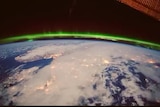 A  bright green line sits above the world as captured from space.