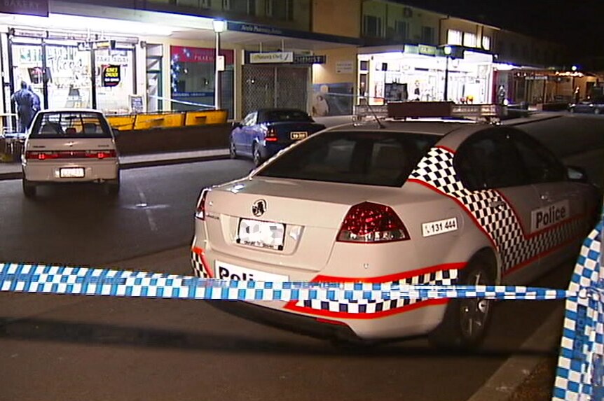 A police car and tape at Ainslie shops at night.