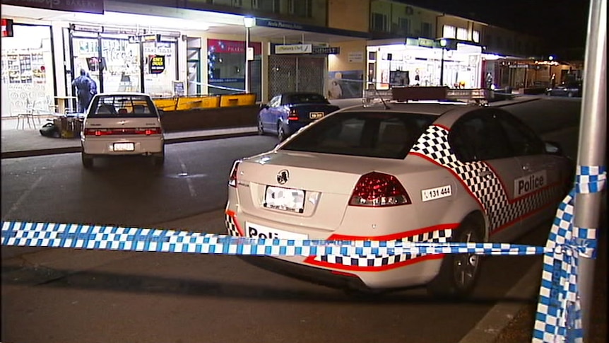 A police car and tape at Ainslie shops at night.