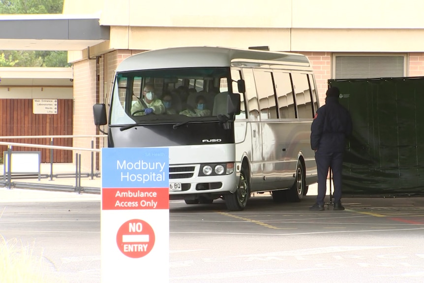 A small bus under a canopy at a hospital