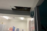An indoor roof panel missing with a first aid sign next to it, hospital supplies lower down