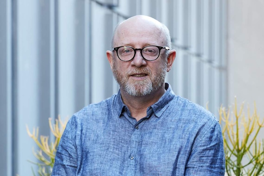 Colour photograph of author Mark O'Flynn standing on top of a city rooftop.