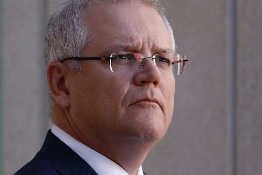 Scott Morrison in a dark blue suit and maroon tie, looks off into the distance.